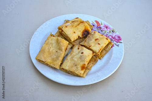Freshly baked appetizing Turkish tortillas - Gozleme with spinach, cheese  on a white board. Space for text. Handmade Turkish traditional pastries. Ispanakli, otlu peynirli gozleme. Tahinli Katmer photo