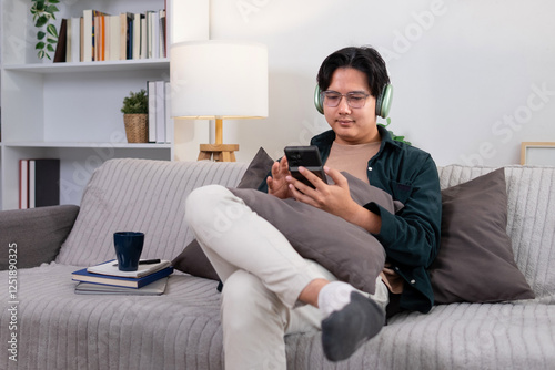 Young man listening to music on the sofa joyfully inside living room
