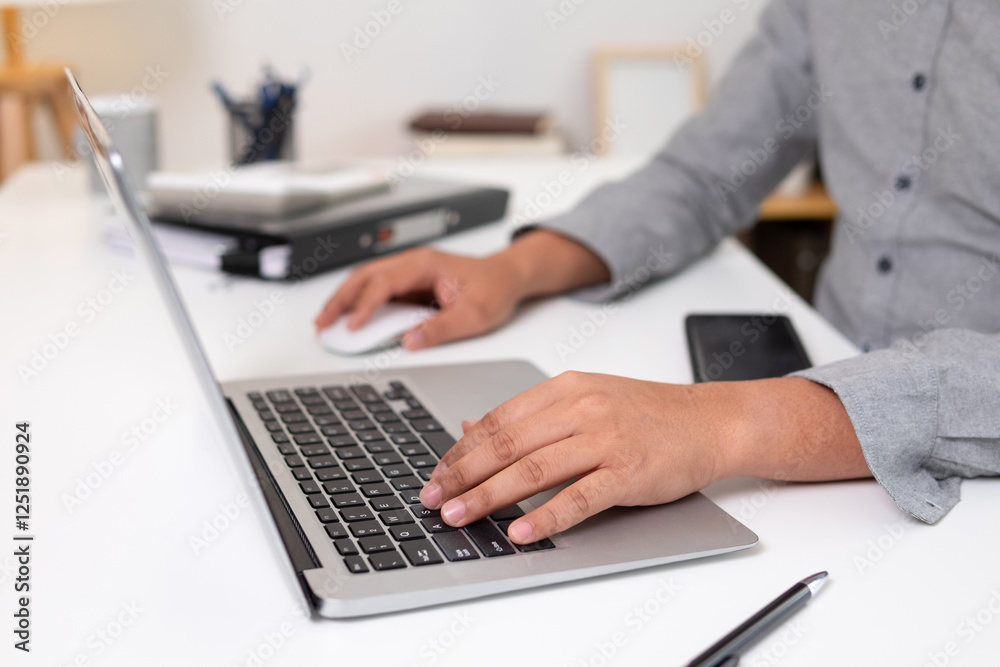 Young man uses his hand to touch a laptop on his desk. Young man uses his hand to touch a laptop on his desk.