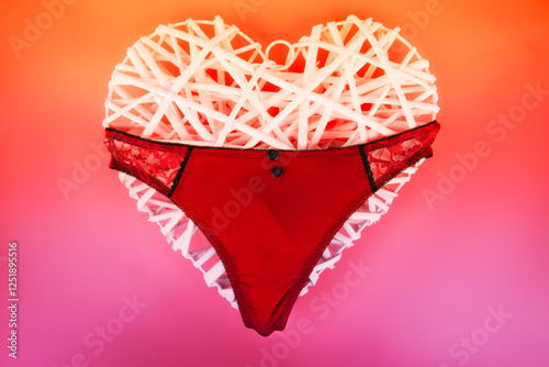 Bold and romantic composition featuring red lace lingerie draped over a white decorative heart on a vibrant gradient background. Perfect for Valentine's Day, fashion ads, or love-inspired designs.
