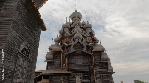 Kizhi Pogost. A historical site dating from the 17th century on Kizhi island. Russian wooden churches stand on a small island. Sunny weather. People walking are visible.