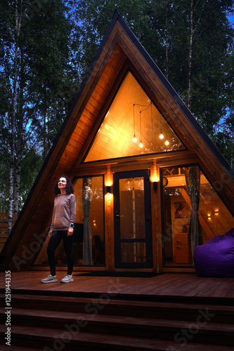 A woman standing in front of a beautiful glamping house in the evening
