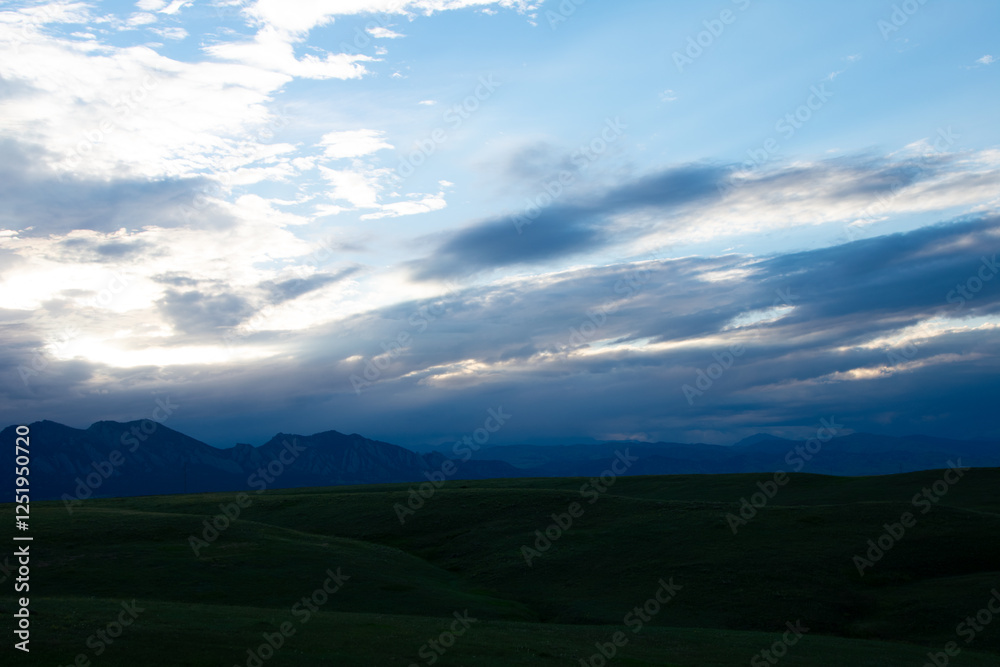 Fototapeta premium Green rolling hills with mountains in the distance