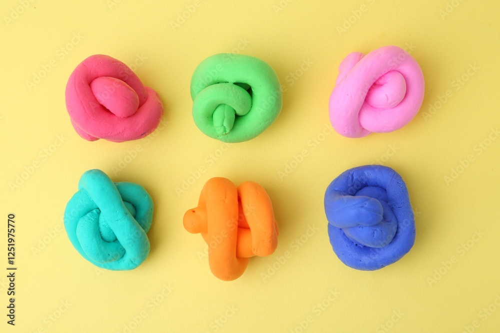 Naklejka premium Different colorful play dough on yellow background, flat lay