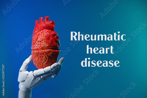 Rheumatism. Robot hand holding model of human heart on blue gradient background with words Rheumatic Heart Disease photo