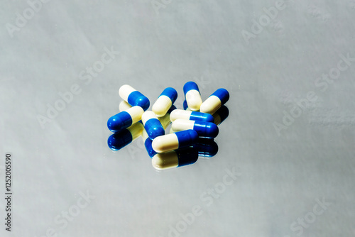 white and blue vitamin pills on a white background with reflection
