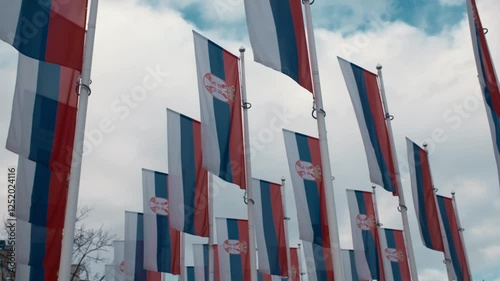 Many Serbian flags on flagpoles are fluttering in the wind. Novi Sad town in Serbia country. Horizontal slow motion 4k footage