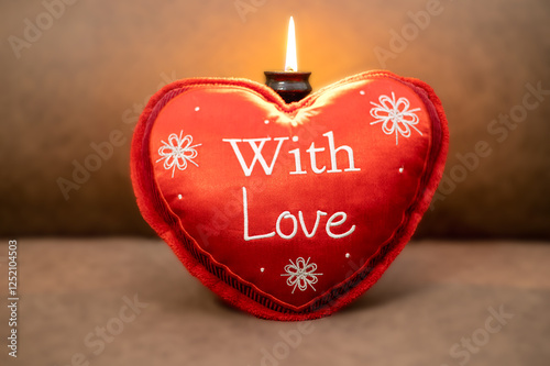 A candle is burning, in front of it is a red pillow with the inscription 