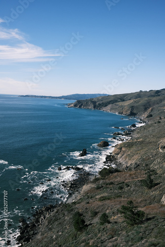 Wallpaper Mural A view of the rugged Pacific coastline with crashing waves against rocky shores. The deep blue ocean stretches to the horizon under a clear sky, capturing the beauty of untouched coastal landscapes. Torontodigital.ca
