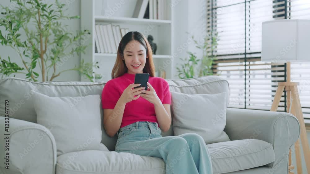 Happy young asian woman relax on comfortable couch at home texting messaging on smartphone, smiling girl use cellphone chatting, online shopping at home, video call communication Happy young asian woman relax on comfortable couch at home texting messaging on smartphone, smiling girl use cellphone chatting, online shopping at home, video call communication
