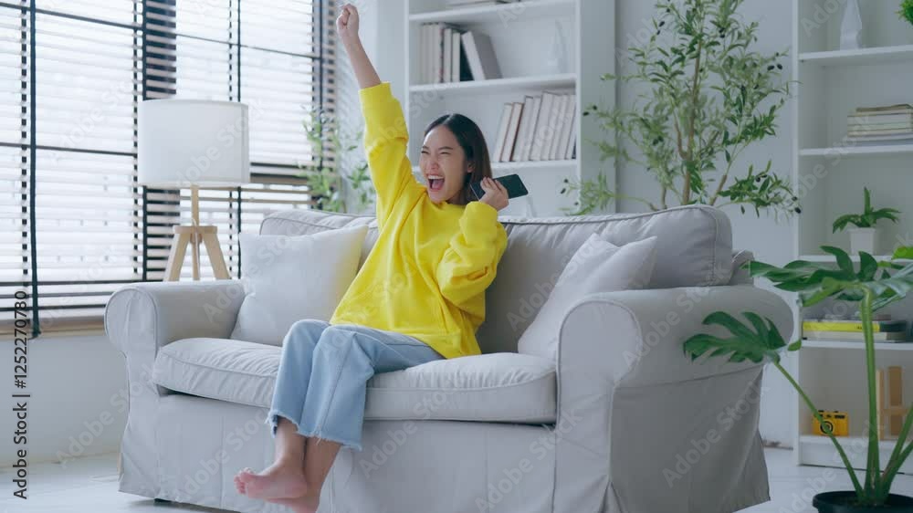 Happy young asian woman relax on comfortable couch at home texting messaging on smartphone, smiling girl use cellphone, chatting online message, shopping online from home