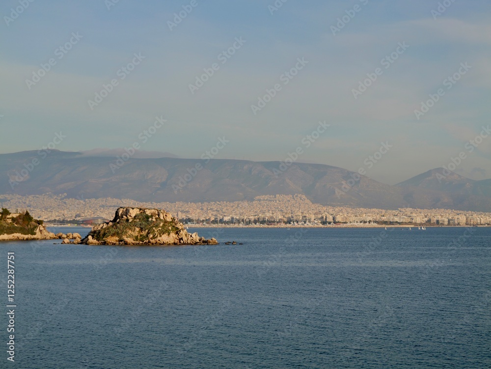 View of the seaside and Hymettus or Hymettos, a mountain range in the Athens area of Attica, from the Votsalakia beach, Piraeus, Greece View of the seaside and Hymettus or Hymettos, a mountain range in the Athens area of Attica, from the Votsalakia beach, Piraeus, Greece