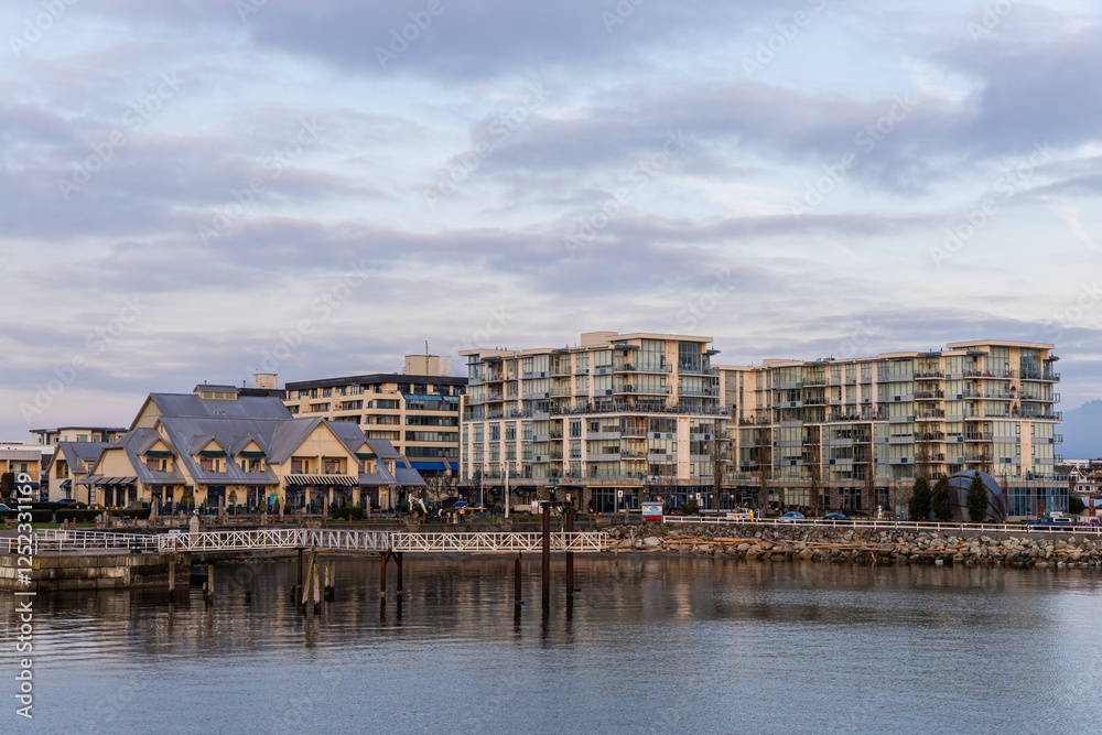 Obraz premium Modern Waterfront Buildings with Pier Under Cloudy Sky