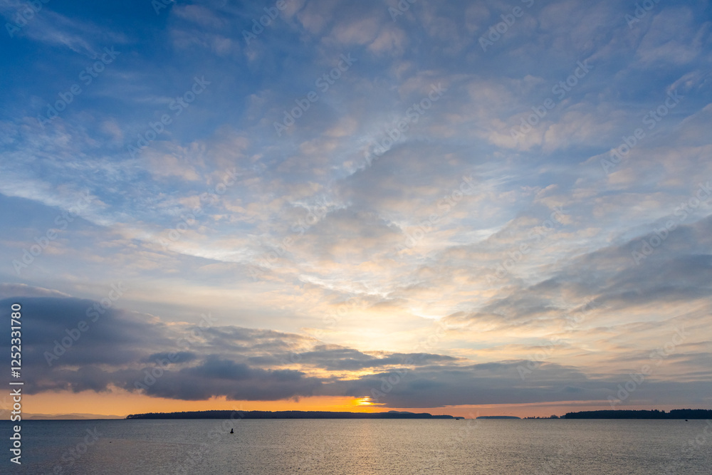 Naklejka premium Serene Sunset Over Coastal Waters with Clouds and Distant Islands