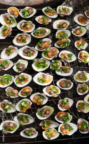 Grilled hairy ark clams with spring onion in oil. Grilled scallops with green onion or so long nuong mo hanh. photo