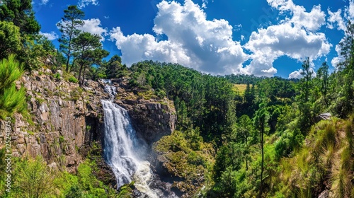Majestic waterfall cascading down rocky cliffs, lush green forest backdrop, sunny day, travel tourism