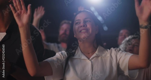 Woman raising hands in spiritual praise during evangelical worship service, joyful expression, white shirt, diverse congregation with hands lifted in celebration of faith