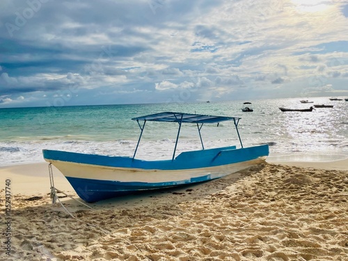 Traditional Wooden Fishing Boat on a Sandy Beach with a Scenic Ocean View in Playa Del Carmen Mexico - concept of travel, holiday, rustic