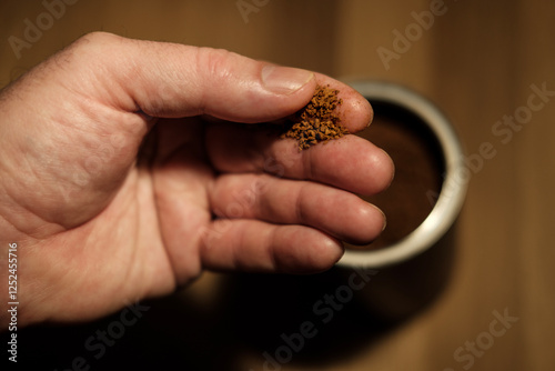 Barista hand holding freeze dried coffee granules above filter photo