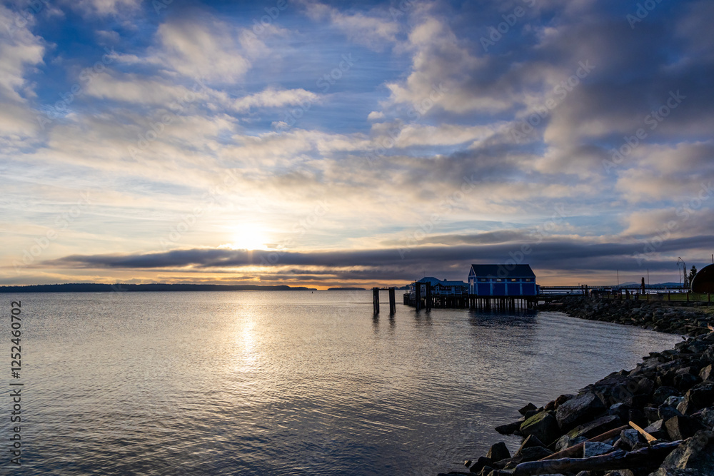 Obraz premium Sunrise Over the Ocean with a Dock and a Coastal Landscape