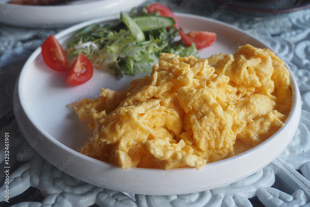 Soft scrambled eggs served with fresh vegetables on a plate Soft scrambled eggs served with fresh vegetables on a plate