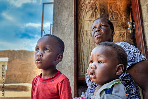 African village , granny and kids , playing in front of the door of the shack house in the yard, daily life in the ghetto