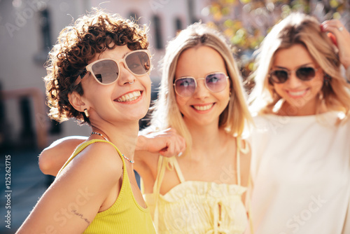 Three young beautiful smiling hipster female in trendy summer stylish clothes. Sexy carefree women posing in the street. Positive models having fun, hugging and going crazy, in sunny day, sunglasses photo