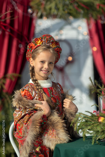 A blonde girl in a national Russian costume on the Maslenitsa holiday. A child in a traditional costume with fur trim and a headdress against a festive backdrop. Winter scene with a beautiful girl