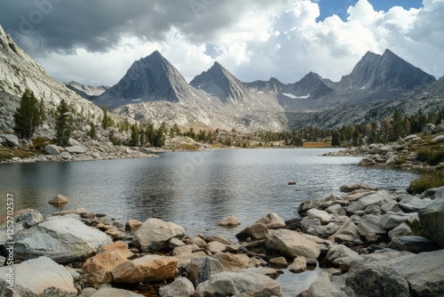 Serene lake surrounded by mountains and grassland in a cloudy atmosphere