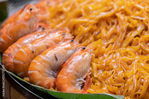 A close-up view of fried Kuey Teow noodles with prawns. The noodles are glossy mixed with juicy prawns