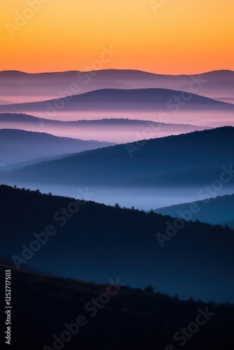 Misty mountain ranges at sunset with layered ridges creating gradient from deep blue to orange sky, showcasing atmospheric perspective. Generative AI