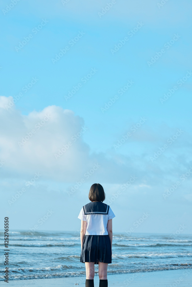 Fototapeta premium 青空と海を背景に立つ女子高校生