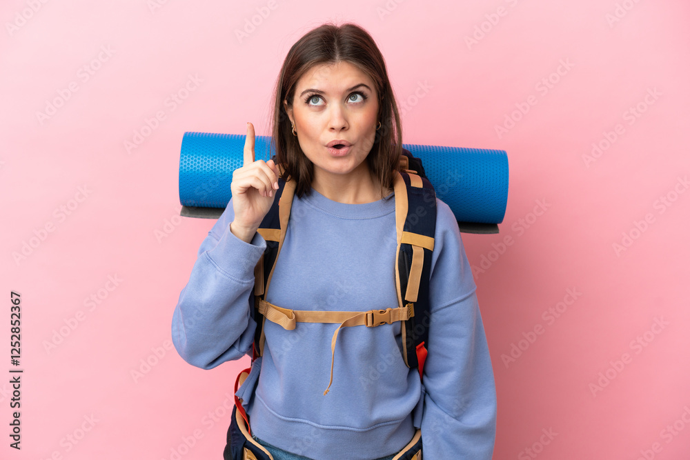 Young mountaineer woman with a big backpack isolated on pink background intending to realizes the solution while lifting a finger up Young mountaineer woman with a big backpack isolated on pink background intending to realizes the solution while lifting a finger up