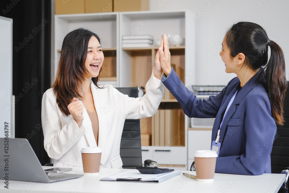 Fototapeta premium Two Asian female business woman sit desk,discussing business investments.They analyze financial data, explore market opportunities, and strategic growth to maximize returns ensure business success