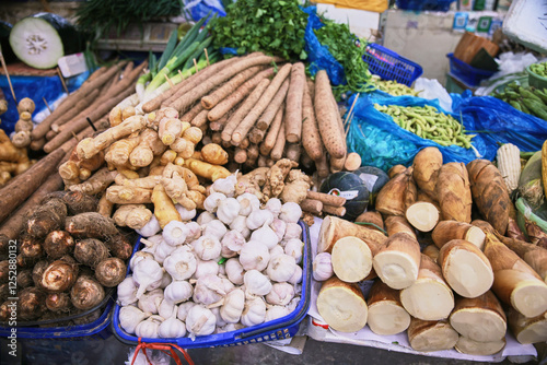 A variety of vegetables are displayed on a table, including garlic, potatoes, and celery. The vegetables are arranged in different bowls and baskets, creating a colorful and inviting display photo