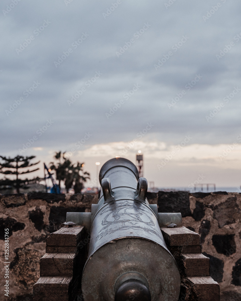A canyon on an ancient fortress by the sea. The cannon is pointing to the sky which is cloudy. A canyon on an ancient fortress by the sea. The cannon is pointing to the sky which is cloudy.