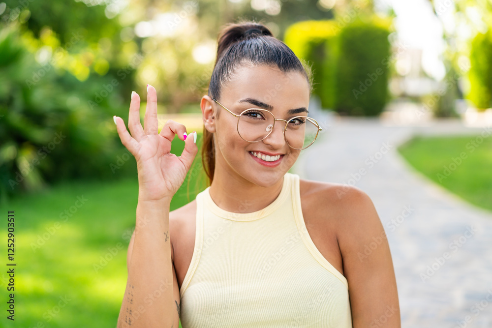 Young pretty woman with glasses at outdoors showing ok sign with fingers Young pretty woman with glasses at outdoors showing ok sign with fingers