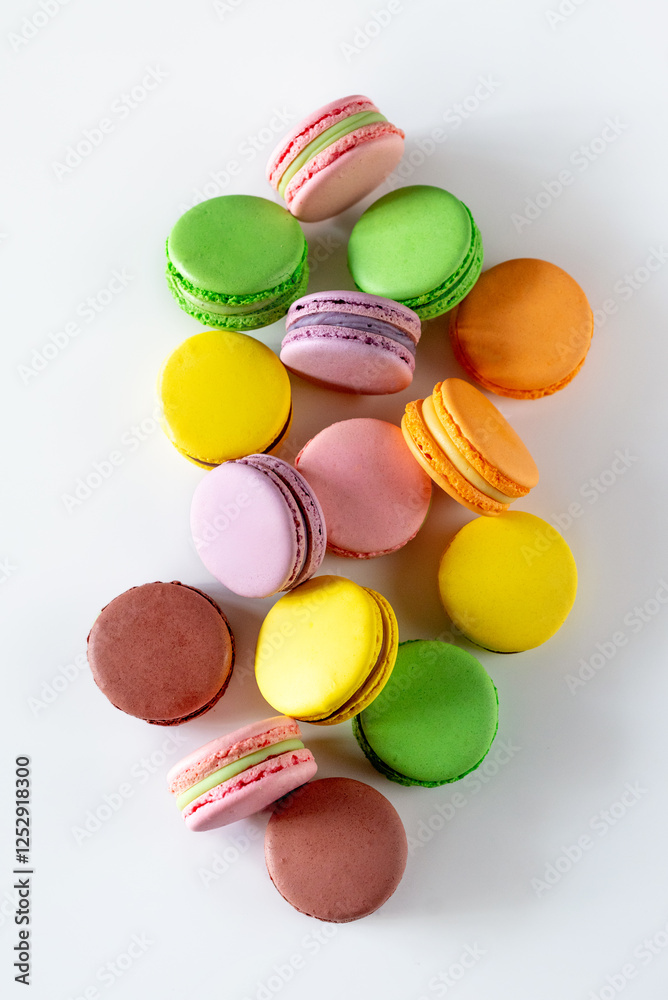 Obraz premium A vibrant assortment of colorful macarons arranged artfully on a white background, showcasing a delightful variety of flavors