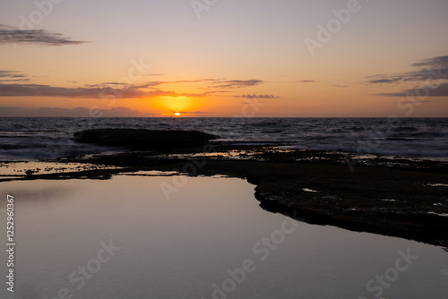 Beautiful sunrise with the sky reflecting in a rock pool along the coast of tamarama beach, Sydney, Australia photo