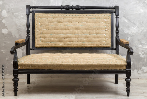 Antique or vintage settee with a dark wood frame and light woven upholstery.