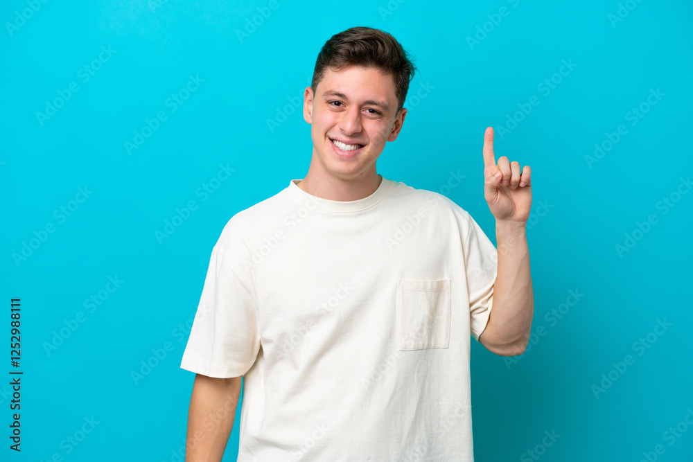 Fototapeta premium Young handsome Brazilian man isolated on blue background pointing up a great idea