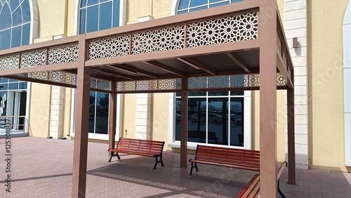 Wooden gazebo with unique oriental patterns and benches in front of a shop in Dubai. photo