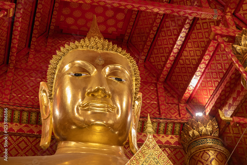 A vertical low angle shot of a big golden Buddha statue in a temple in Ayutthaya, Thailand. The golden Buddha statue of Sam Po Kong at Wat Phanan Choeng .