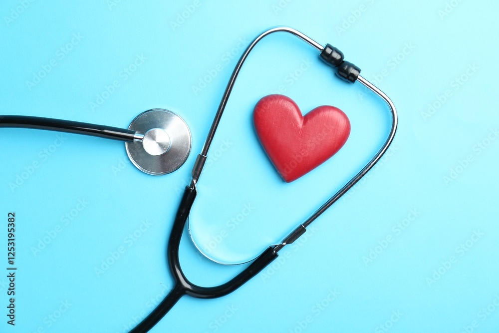 Cardiology. Stethoscope and red decorative heart on light blue background, flat lay Cardiology. Stethoscope and red decorative heart on light blue background, flat lay