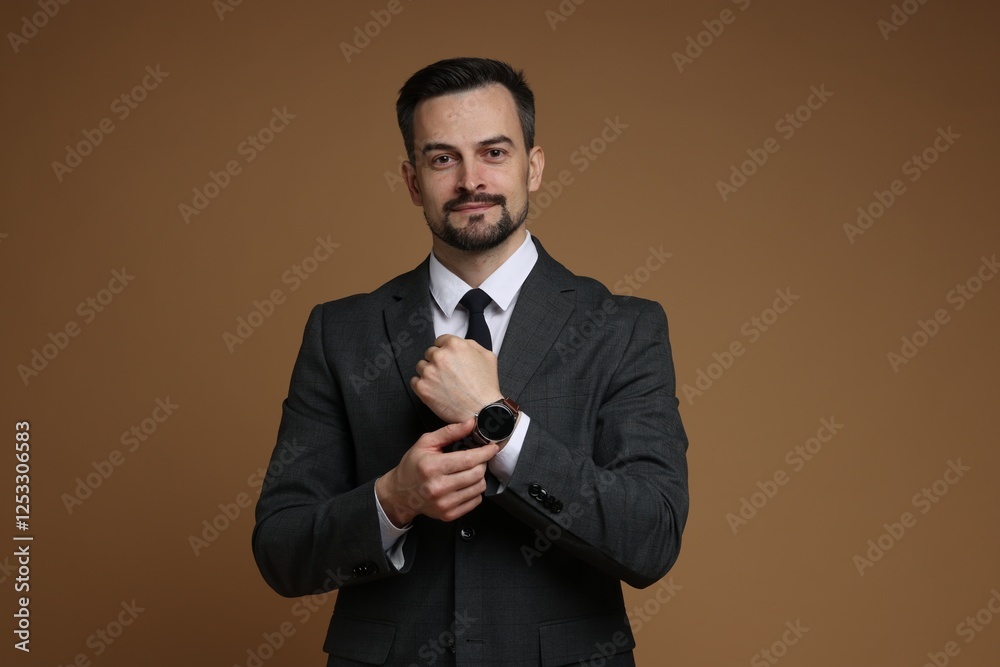 Confident man in classic suit with stylish watch on brown background Confident man in classic suit with stylish watch on brown background