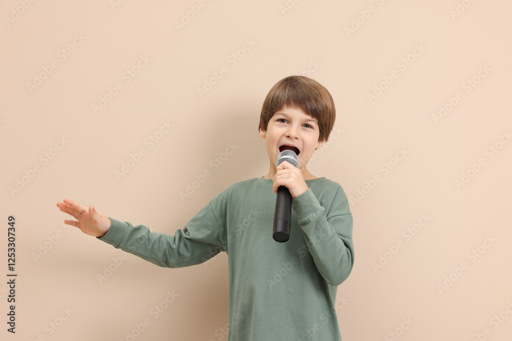 Cute boy with microphone singing near beige wall Cute boy with microphone singing near beige wall