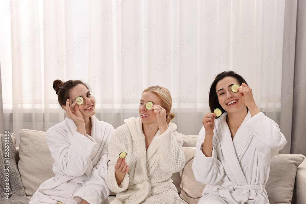 Happy women with cucumber slices on sofa in spa Happy women with cucumber slices on sofa in spa