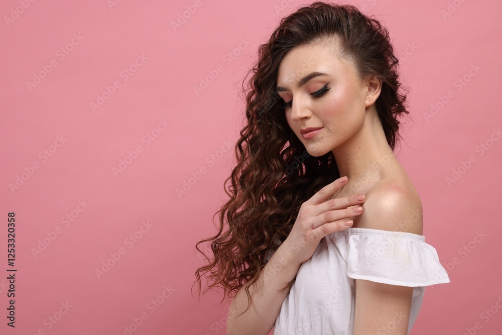 Naklejka premium Beautiful young woman with long curly brown hair on pink background, space for text