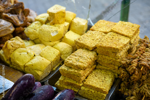  Tofu and tempeh, popular Indonesian ingredients, on display at a market or food stall.  Ready for cooking