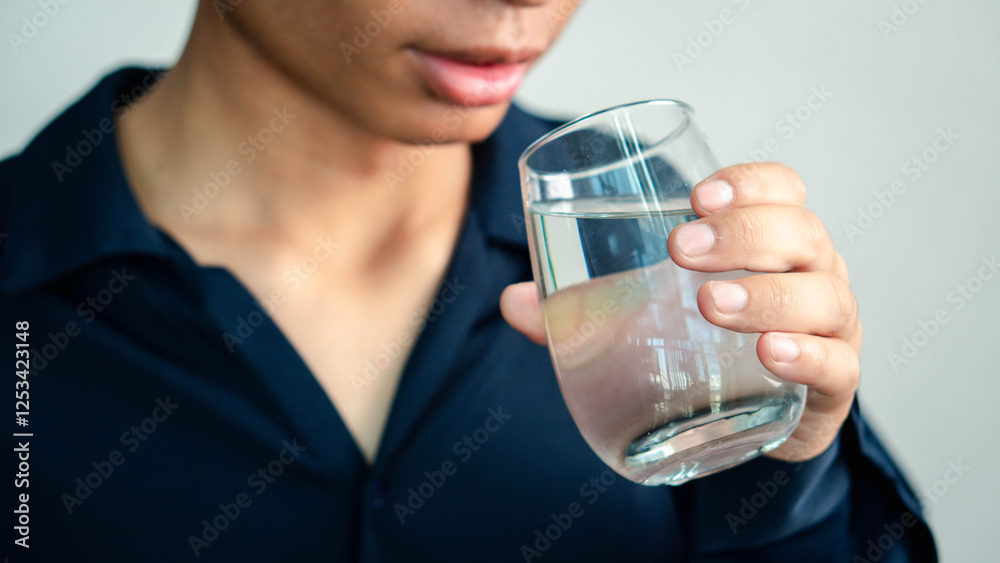 Man Drinking Water, man holding glass drinks still water preventing dehydration, helps maintain normal bowel function and balance of body, skin and health care, healthy lifestyle concept Man Drinking Water, man holding glass drinks still water preventing dehydration, helps maintain normal bowel function and balance of body, skin and health care, healthy lifestyle concept